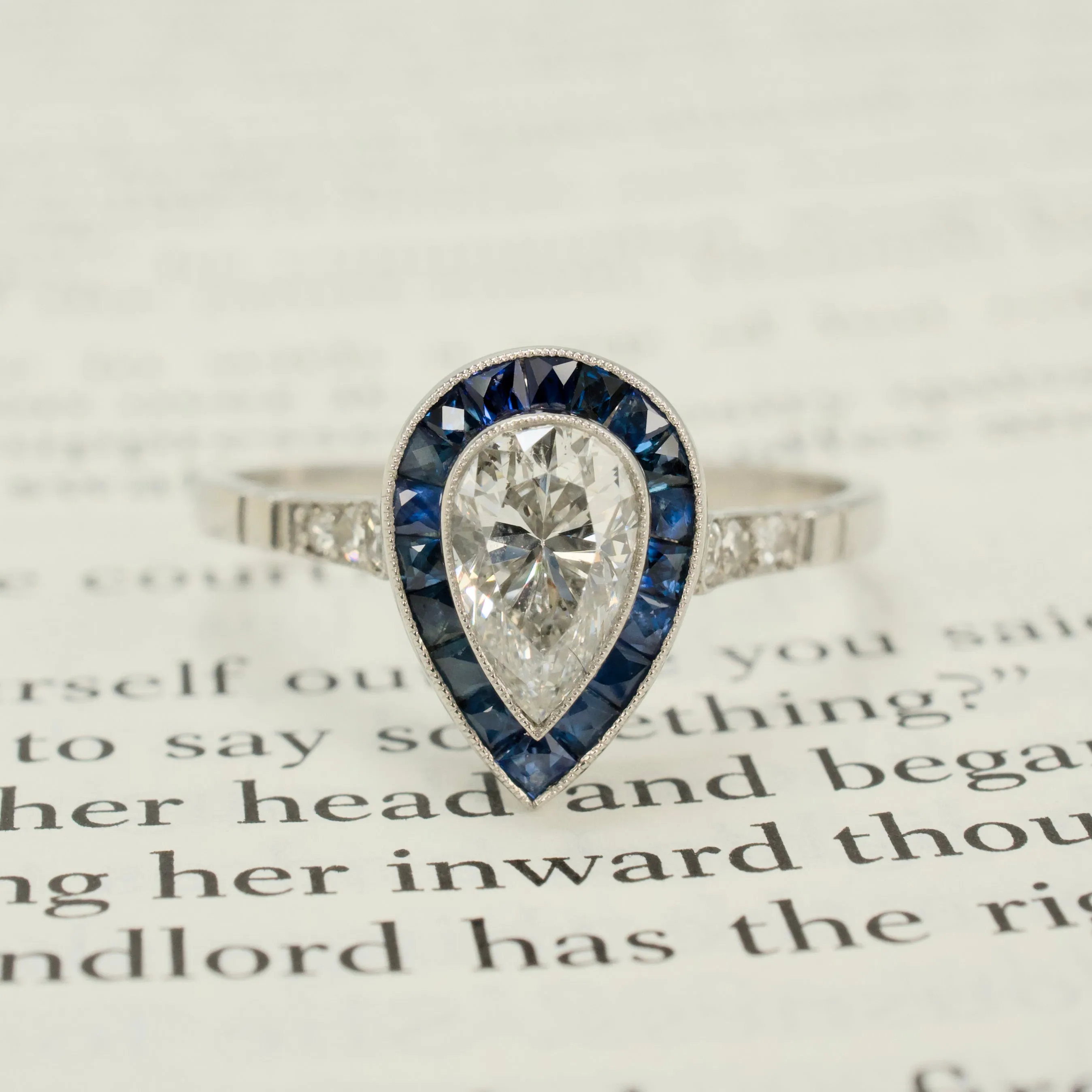 Art Deco Style Platinum Ring with 0.69 Carat Pear Cut Diamond and Sapphire Halo